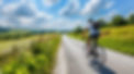 cyclist-riding-through-scenic-countryside-road-with-lush-green-fields-blue-sky-enjoying-le